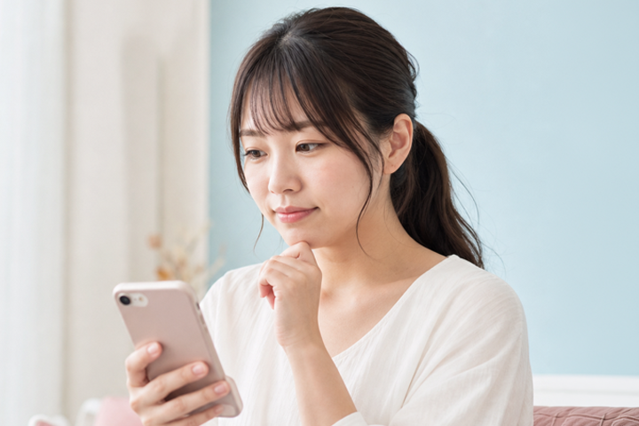 スマートフォンを見ながら仕事内容を確認する成人女性